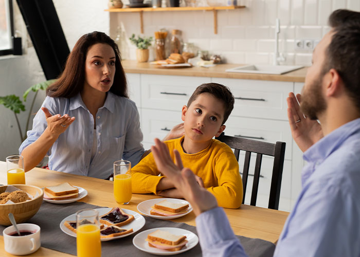 Woman arguing with conservative uncle during Thanksgiving dinner with family and a child at the table.