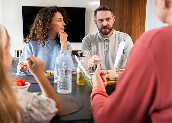 Family members in tense discussion around the dining table during a Thanksgiving dinner with conservative uncle present