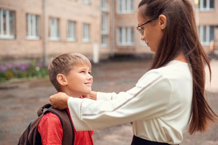 Young boy at school with teacher, highlighting issue of 5YO left hungry after snack denied as consequence for fighting.