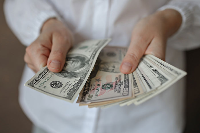 Person in white shirt holding and counting cash representing inheritance dispute and family traditions conflict.
