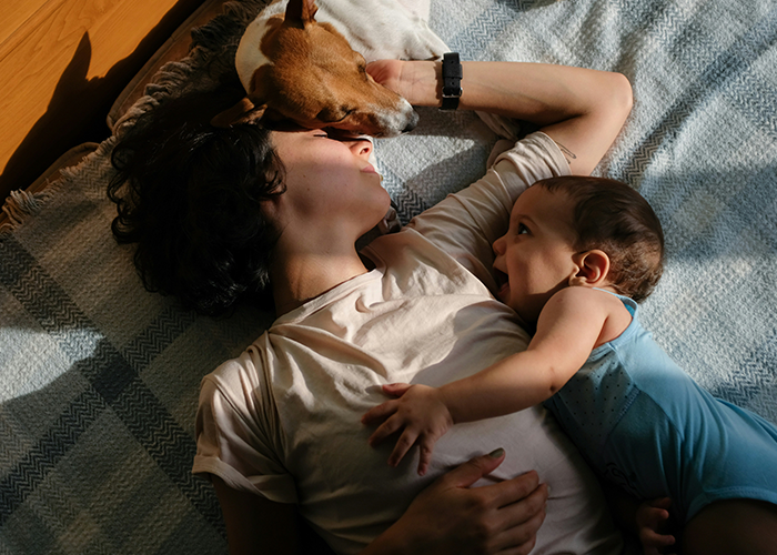 Woman lying with baby and dog, symbolizing bond and emotions related to future stepkid and family struggles.
