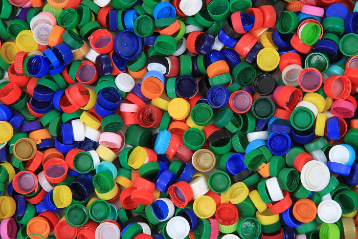 Colorful plastic bottle caps scattered randomly, representing odd childhood things people did that weren’t exactly normal.