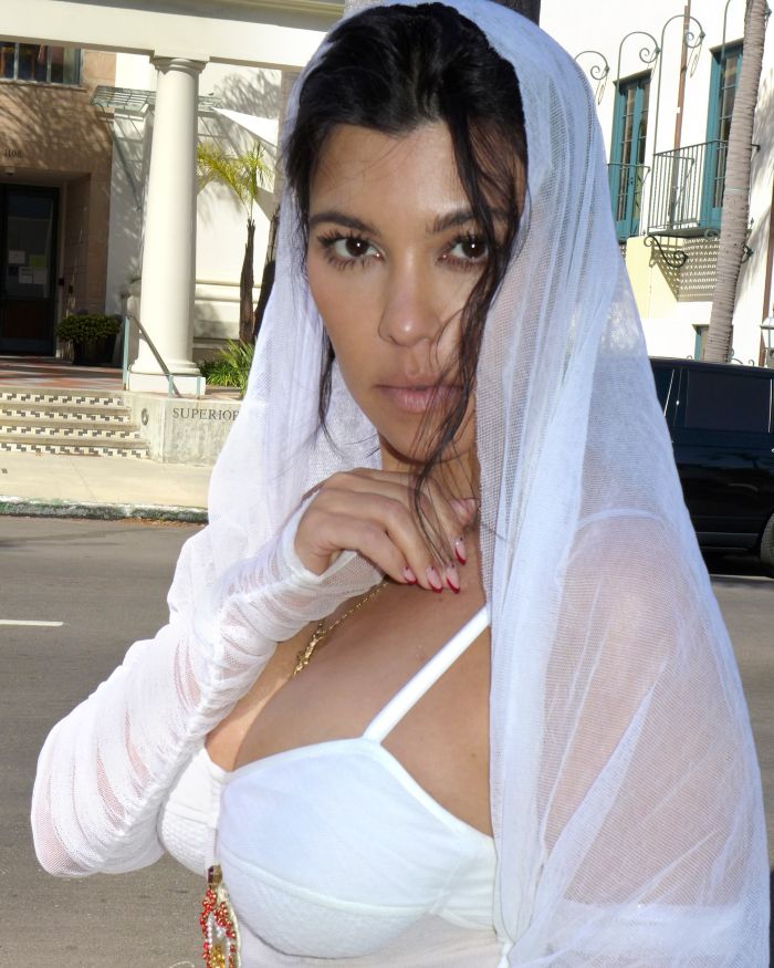 Kourtney Kardashian wearing white sheer fabric outdoors, promoting lollipops for women&rsquo;s private parts with playful reactions.