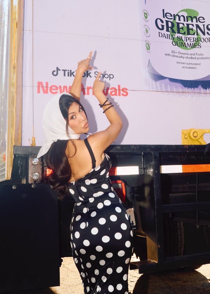 Woman in polka dot dress pointing upwards, related to Kourtney Kardashian lollipops for women&rsquo;s private parts launch and reactions.