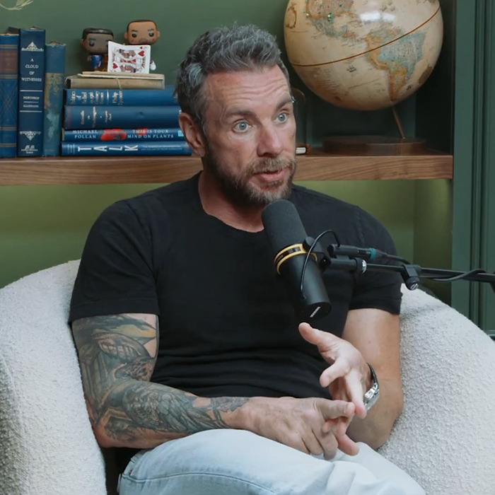 Man with tattoos speaking into a microphone during podcast discussing Kristen Bell and Dax Shepard blackout fights and toxic marriage.