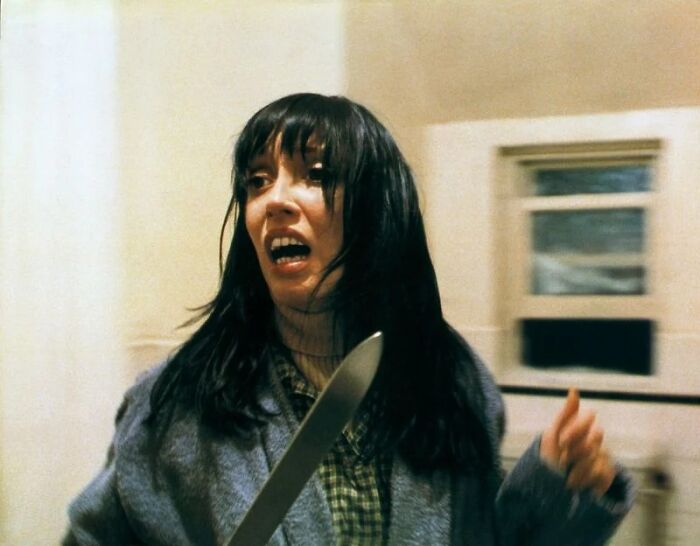 Woman holding a knife in a tense movie scene depicting unrealistic women movie tropes in film.