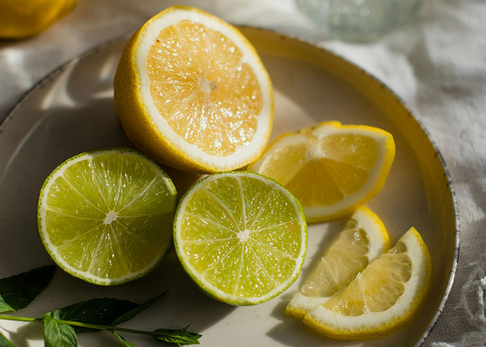 Close-up of sliced lemons and limes on a plate, highlighting fresh citrus fruits with natural lighting.