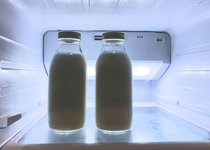 Two glass bottles filled with milk inside a refrigerator, highlighting facts about steak coming from cows.