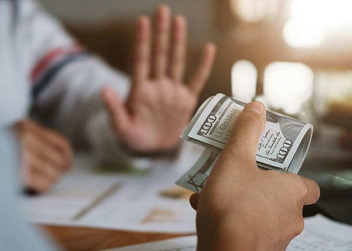 Person holding money with another person showing a stop gesture, illustrating a surprising fact about steak coming from cows.