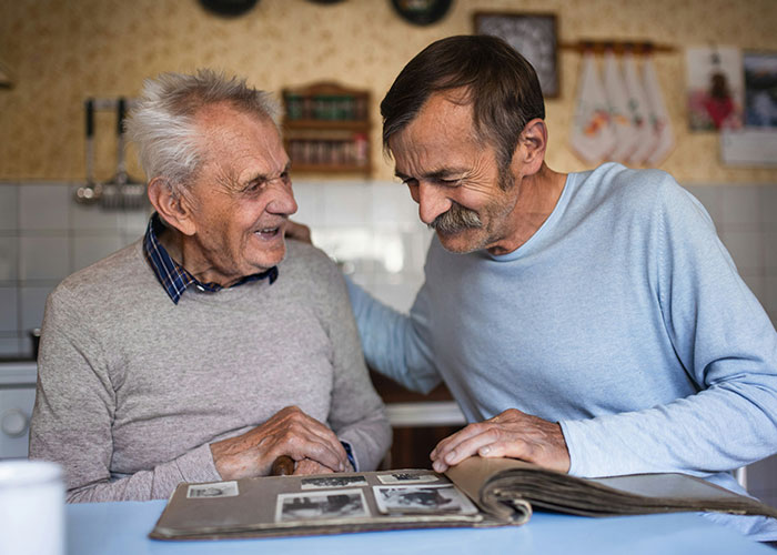 Two men smiling and looking at a photo album together, sharing a moment about steak and cows facts.