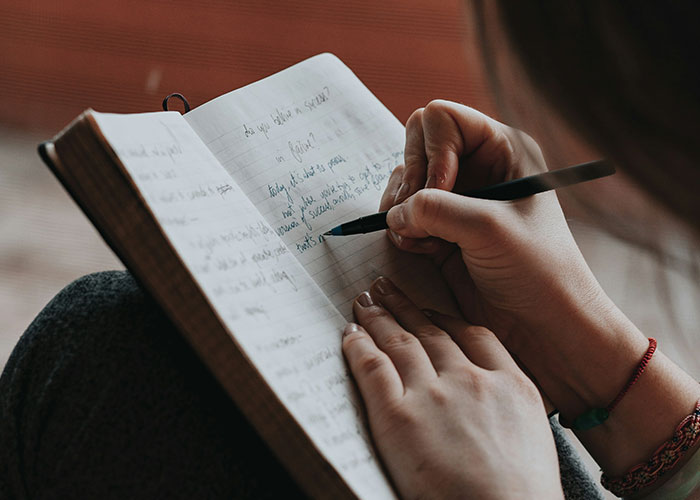 Person writing notes in a journal, reflecting on facts about steak coming from cows in a cozy setting.