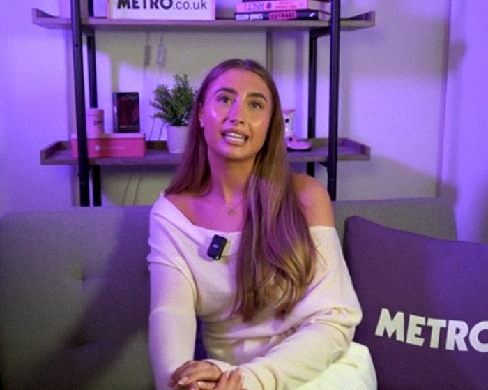 Lily Phillips speaking in an interview setting with Metro-branded cushions and shelves in the background.