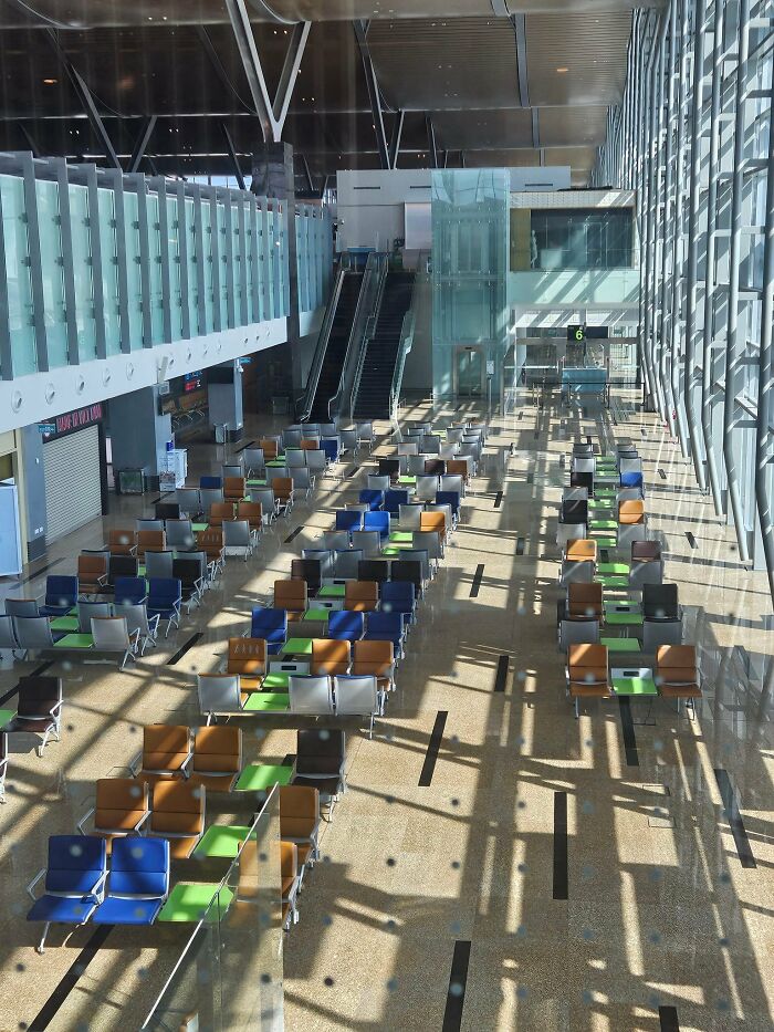 Empty airport waiting area with colorful seats and glass walls, showcasing a beautiful yet unnerving liminal space.