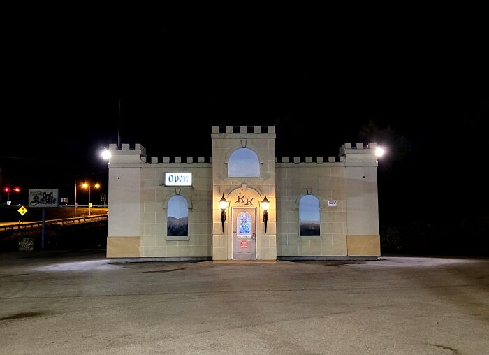 Small castle-like building lit at night in a liminal space with an open sign, creating a beautiful yet unnerving atmosphere.