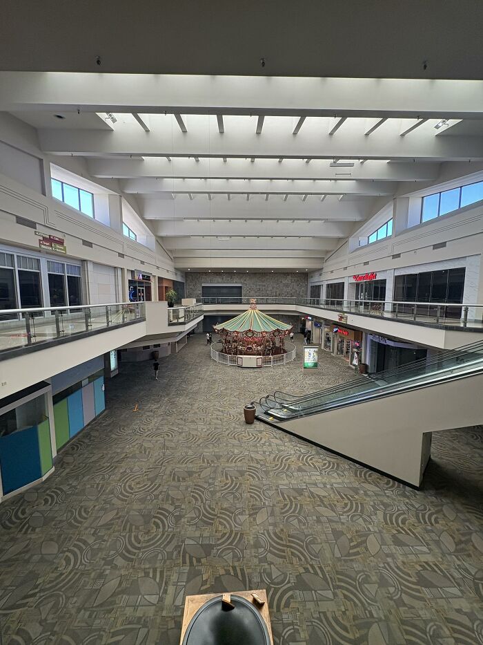 Empty shopping mall with escalator and carousel, showcasing beautiful yet unnerving liminal spaces and empty interiors.