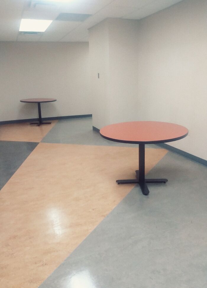 Empty liminal space with two round tables, pale walls, and geometric floor patterns creating an unnerving atmosphere.