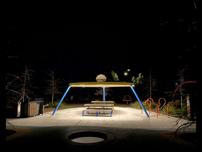 Empty playground area at night under artificial lighting, showcasing an unnerving liminal space atmosphere.