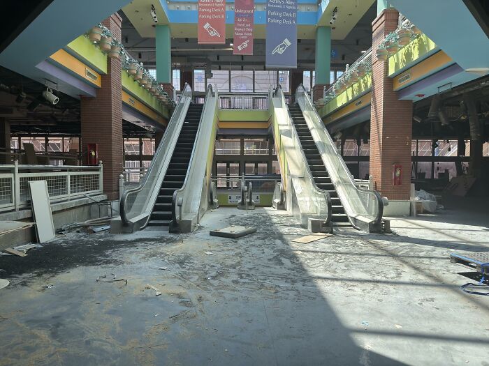Abandoned empty mall with broken escalators and debris, showcasing beautiful yet unnerving liminal spaces.