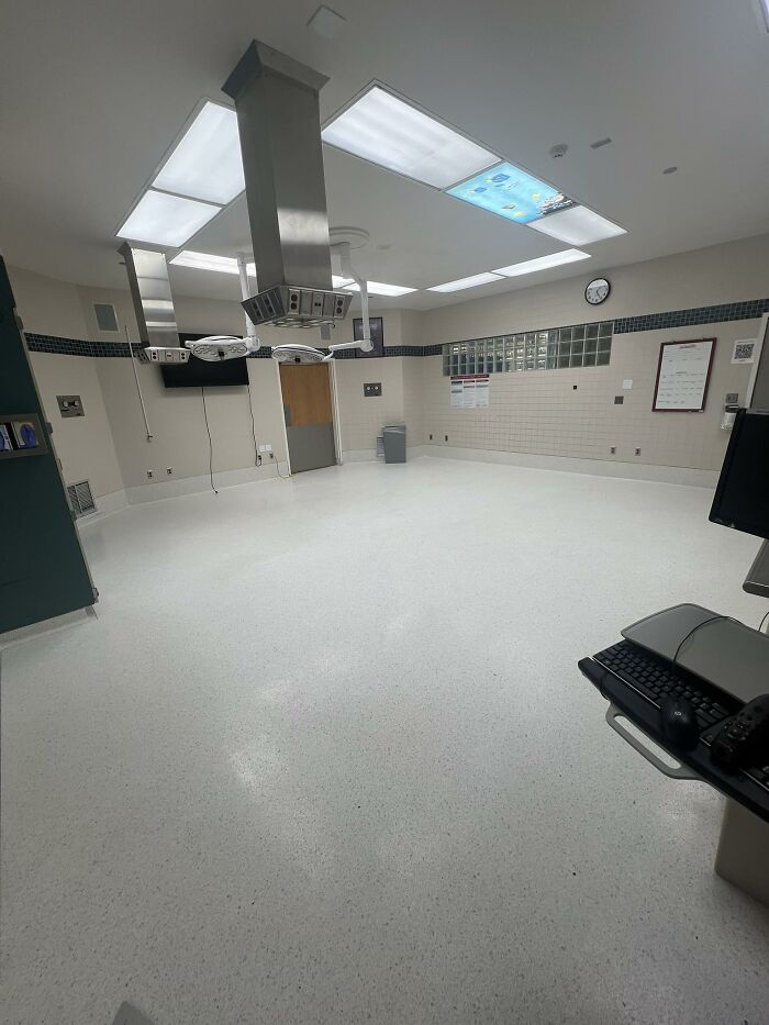 Empty clinical room with bright ceiling lights and sterile white floors, evoking beautiful yet unnerving liminal spaces.