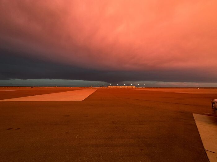 Empty airport runway under an unnerving crimson sky, showcasing a beautiful yet liminal space at dusk.