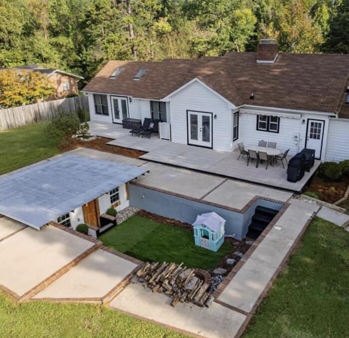 Sunken backyard patio with seating and playground, showcasing a beautiful yet unnerving liminal space design.