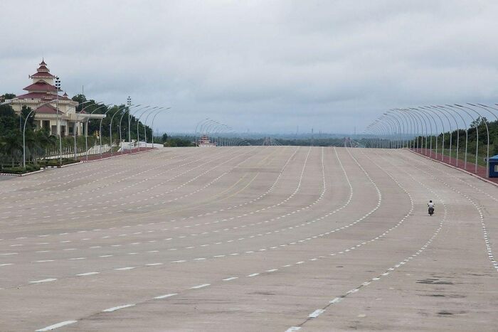 Empty vast highway with a lone motorbike, showcasing beautiful yet unnerving liminal space under cloudy skies.