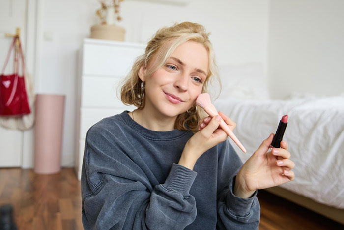 Teen girl applying makeup in bedroom, illustrating stepsister using gifts without permission and setting family boundaries.
