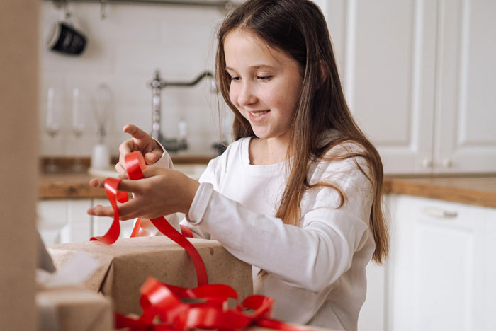 Young girl happily opening gifts, illustrating stepsister using presents without permission and family tensions over boundaries.