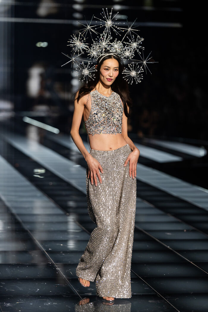 Model wearing sparkling silver outfit and starburst headpiece on runway showcasing Victoria's Secret fashion show looks