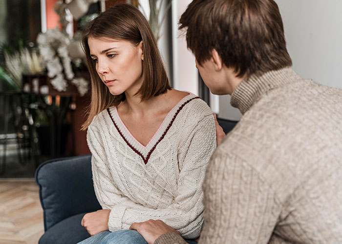 Young woman looks worried while boyfriend comforts her as they discuss saving niblings from foster care and future plans.
