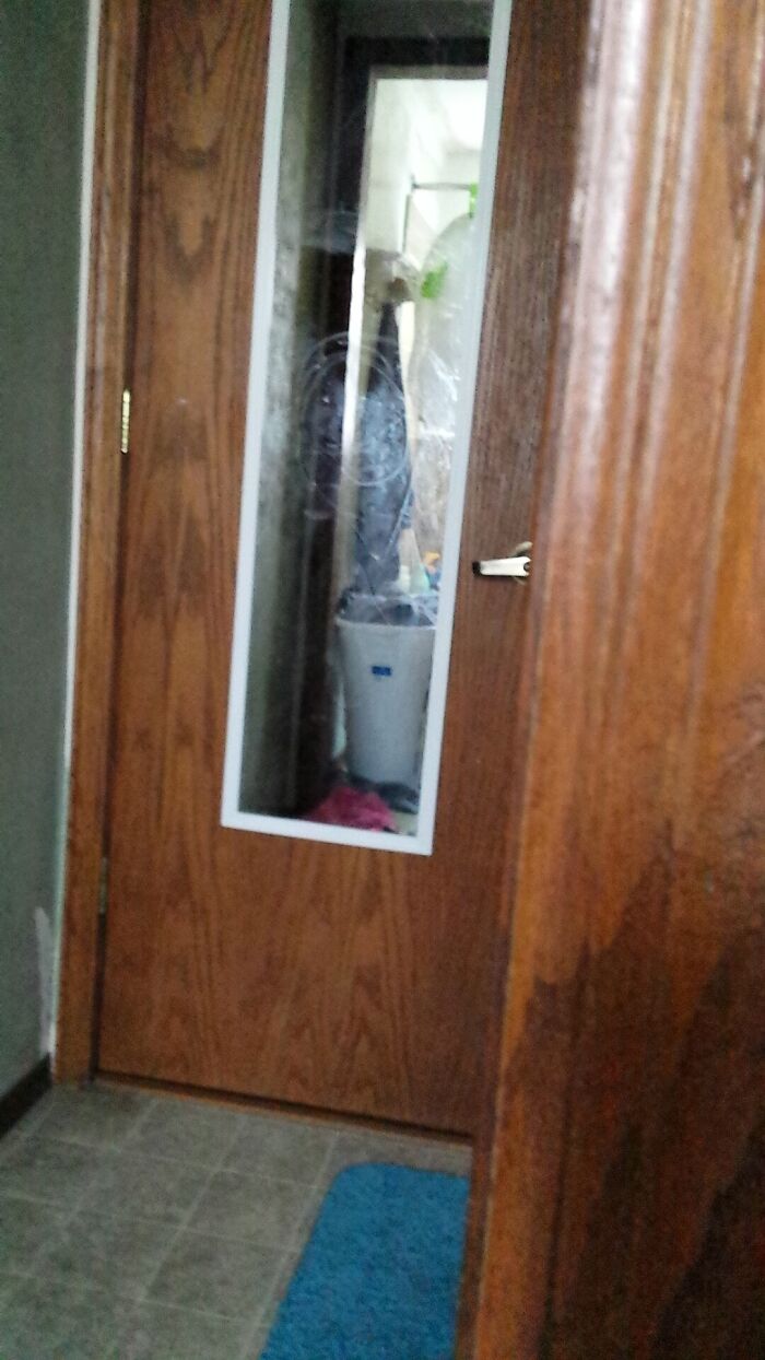 Reflection in a door mirror creating a creepy illusion resembling a ghostly figure in a dim hallway setting.