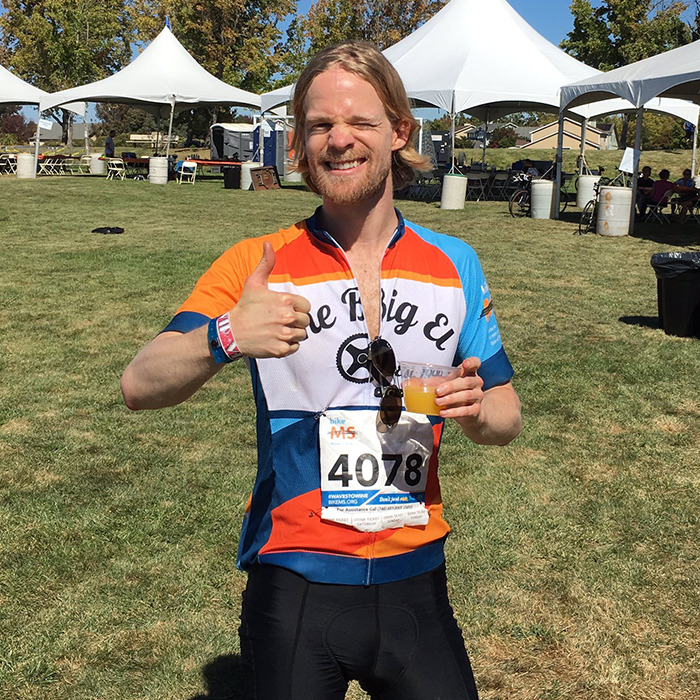 Man behind blinking guy GIF giving thumbs up at outdoor cycling event wearing race number 4078 and colorful jersey.