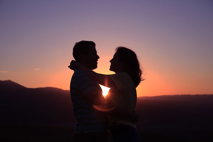 Silhouette of a young couple embracing at sunset, symbolizing a 19YO choosing parents over 27YO girlfriend and child.
