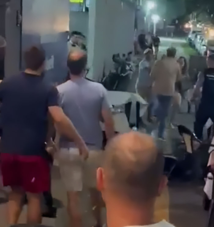 Crowd intervention on a busy street as a man reacts after a woman threw a chair at a kid in a viral children come first debate.