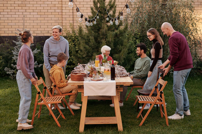 Family gathering in backyard for lunch, highlighting a tense moment involving a daughter-in-law and a man at the table.