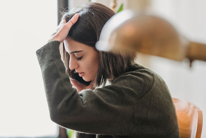 Woman looking distressed while on a phone call, illustrating a daughter-in-law calling to join daughters' lunch.