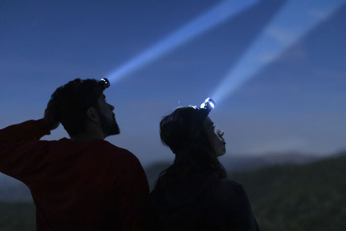 Two people wearing headlamps exploring outdoors at night, highlighting mysteries that once baffled the world now solved.