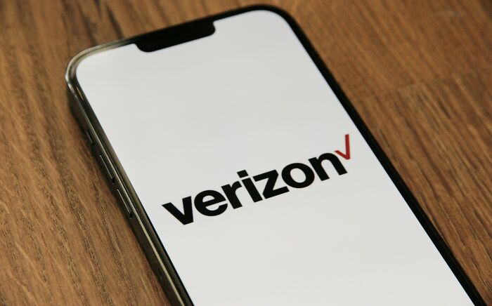 Smartphone displaying Verizon logo on wooden surface, illustrating long grudges held by 36 people and their reasons.