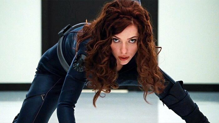 Woman in a black tactical suit crawling on the floor, illustrating unrealistic women movie tropes in action scenes.