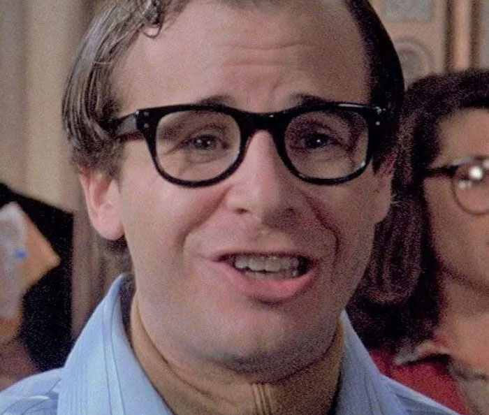 Man wearing black glasses smiling warmly, expressing kindness and positivity, highlighting men are good.