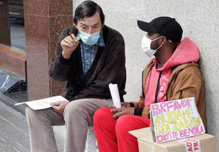 Two men wearing masks having a conversation on the street, highlighting men are good through acts of kindness.