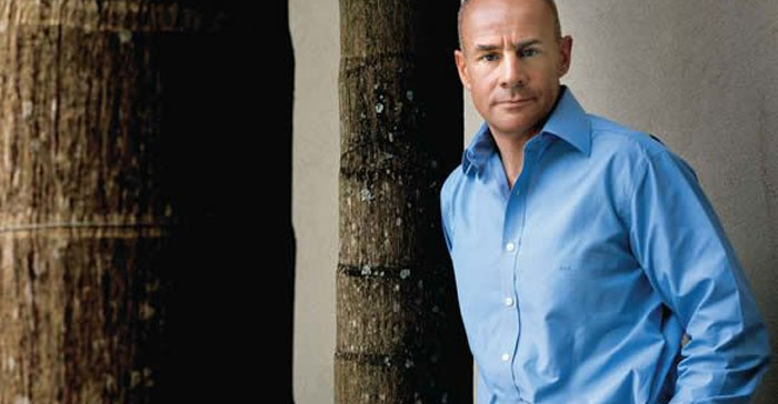 Man standing outdoors between trees, wearing a blue shirt, representing men are good in the world.