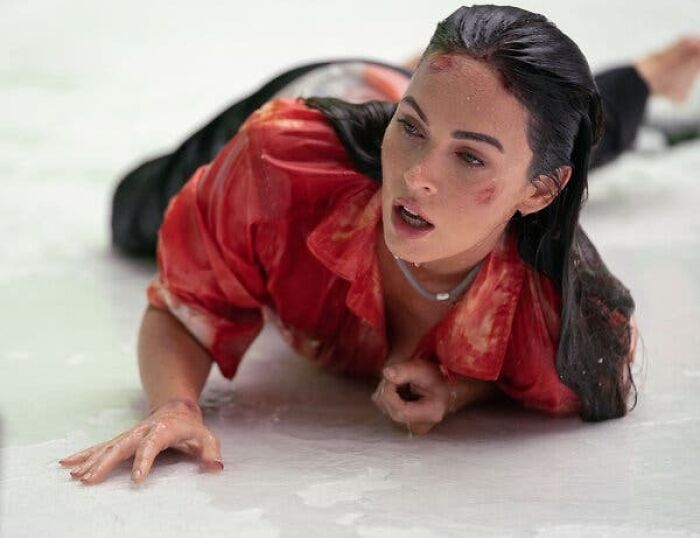 Woman in a red shirt lying on the floor with bruises, illustrating unrealistic women movie tropes in film scenes.
