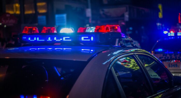 Police car with flashing red and blue lights at night, illustrating chaotic scenes from disastrous playdates parents wish to forget.