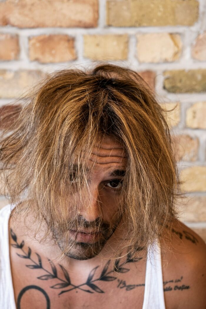 Man with messy hair and tattoos looking down, illustrating first signs that scream someone is having an affair.