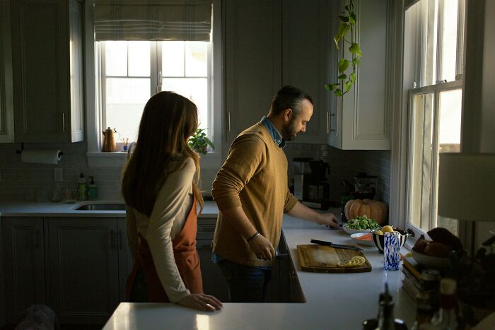 Couple sharing relationship advice while preparing food together in a cozy kitchen, focusing on connection and communication.