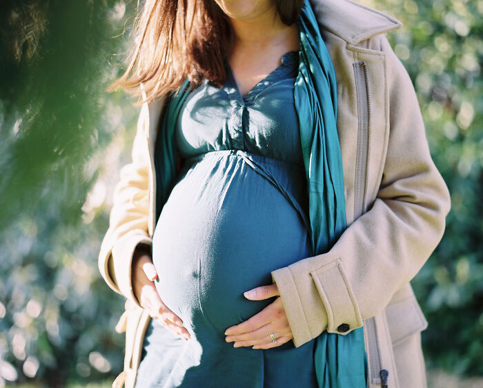 Pregnant woman outdoors, hands gently on belly, illustrating moments the universe had people’s back and protected them from harm.