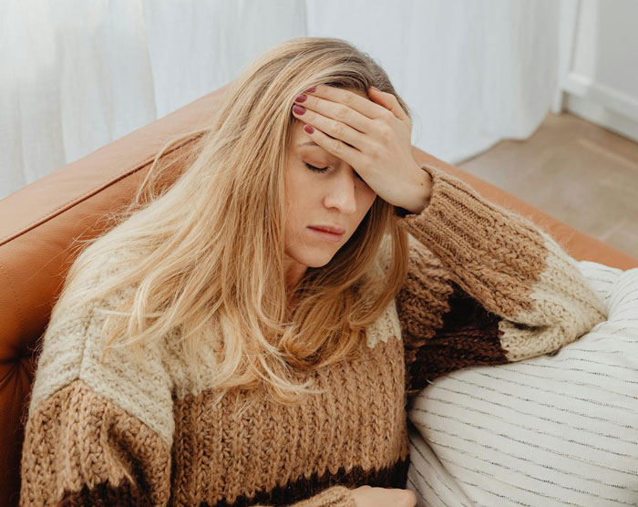 Woman wearing a brown knitted sweater looking stressed, illustrating MIL trying to be the center of attention during wedding.