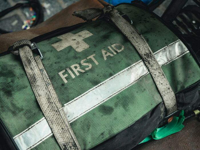 Worn green first aid kit bag with straps, illustrating simple car stuff for basic emergency preparedness skills.