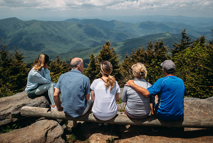 Five people sitting on a log overlooking mountains, illustrating moments of misread social cues and awkward interactions.